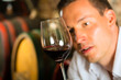 Mann testet Wein im Hintergrund Weinfässer