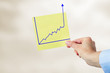 Hand holding paper with rising chart