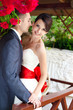 bride and groom posing in the arbor under red roses
