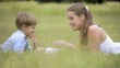Mother helping son with homework, laying down on grass