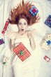 Redhead girl in bed with gifts. Photo in warm tone style.