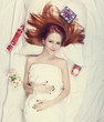 Redhead girl in bed with gifts. Photo in warm tone style.