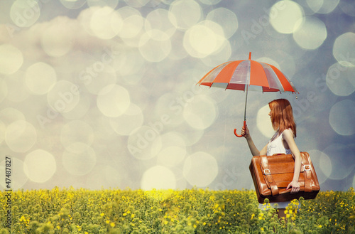 Photo: Redhead enchantress with umbrella and suitcase at spring rapesee Redhead enchantress with umbrella and suitcase at spring rapesee