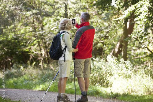 Photo: A mature couple walking, navigating with a smartphone A mature couple walking, navigating with a smartphone