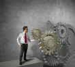Businessman turning a gear system