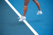 Female tennis player on blue court in a mid-serve jump