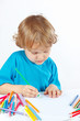 Little cute blond boy draws with color pencils