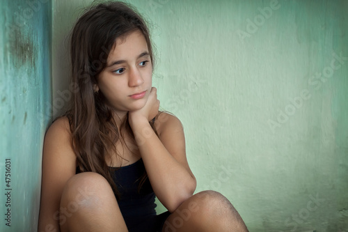 Photo: Sad and lonely hispanic girl sitting in a corner Sad and lonely hispanic girl sitting in a corner