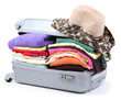 Closed silver suitcase with clothing isolated on white
