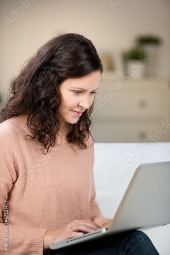 Photo: frau sitzt mit laptop auf dem sofa frau sitzt mit laptop auf dem sofa