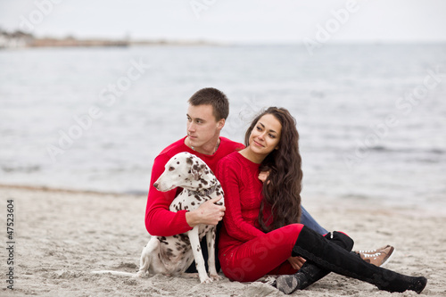 Photo: attractive romantic couple with a dog having fun on the beach attractive romantic couple with a dog having fun on the beach