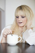junge blonde  Frau am gähnen vor Müdigkeit mit Tasse Kaffee