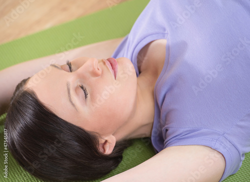 Photo: Portrait of a young fitness woman lying on a yoga mat and exerci Portrait of a young fitness woman lying on a yoga mat and exerci