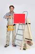 woodworker holding a painted ad board