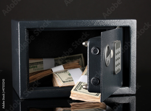 Photo: Money in open safe isolated on black Money in open safe isolated on black