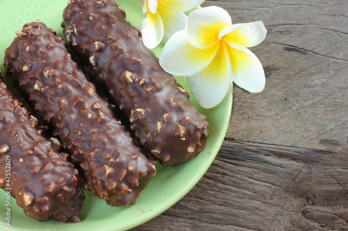 Photo: Chocolate drop on a wooden floor with white flowers Chocolate drop on a wooden floor with white flowers