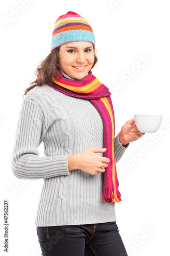 Photo: Young female with hat and scarf holding a cup of tea Young female with hat and scarf holding a cup of tea