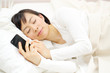 スマートフォンを持ったまま寝る女性