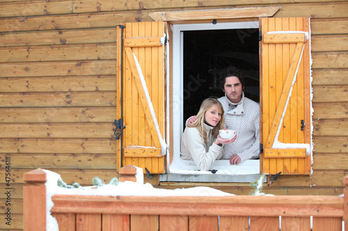 Photo: Couple looking out from chalet window Couple looking out from chalet window