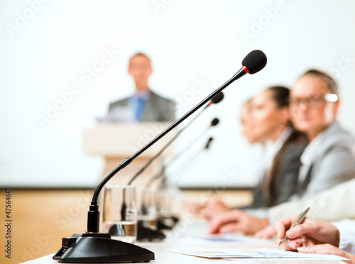 Photo: microphone stand in the row in front of businessmen microphone stand in the row in front of businessmen