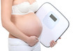 A cropped picture of a pregnant woman with a scale.