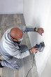 Man using power sander on wall
