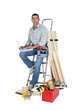 Handyman sitting on a ladder with laptop