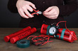 Human makes timebomb on wooden table on black background