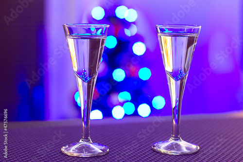 Photo: Two glasses of vodka with blurry christmas tree background Two glasses of vodka with blurry christmas tree background