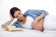 Pregnant brunette laying in bed reading
