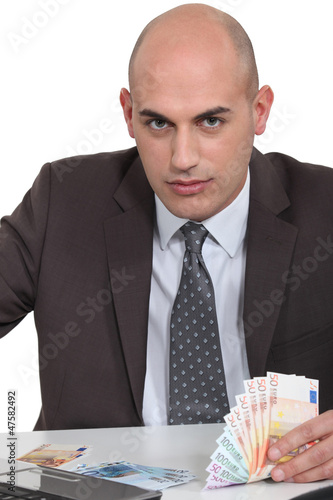 Photo: Bald man with laptop and money Bald man with laptop and money