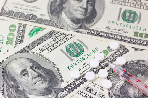 Photo: Syringe and pills. US dollars in the background. Syringe and pills. US dollars in the background.