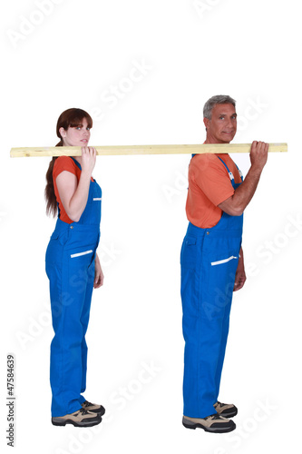 Photo: Labourers carrying a wooden plank Labourers carrying a wooden plank