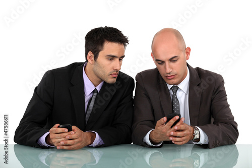 Photo: Businessmen comparing phones Businessmen comparing phones