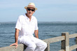 Senior in a straw panama hat sitting by the water