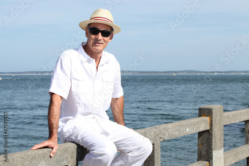 Photo: Senior in a straw panama hat sitting by the water Senior in a straw panama hat sitting by the water