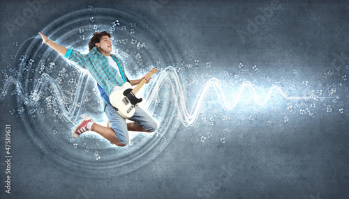 Photo: young man playing on electro guitar and jumping young man playing on electro guitar and jumping
