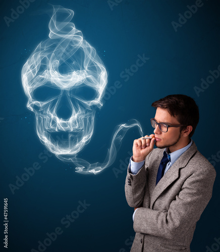 Photo: Young man smoking dangerous cigarette with toxic skull smoke Young man smoking dangerous cigarette with toxic skull smoke