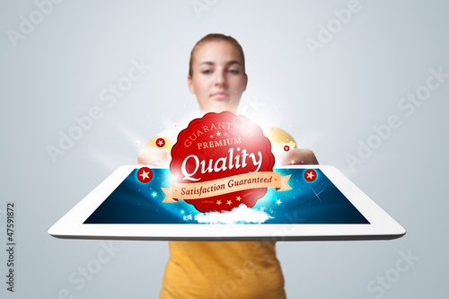 Photo: woman holding tablet with red quality label in clouds woman holding tablet with red quality label in clouds