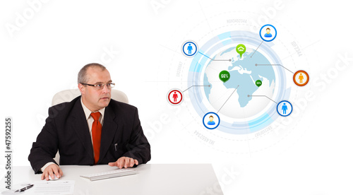 Photo: businessman sitting at desk and typing on keyboard with globe an businessman sitting at desk and typing on keyboard with globe an