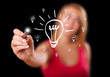 Woman drawing light bulb on whiteboard