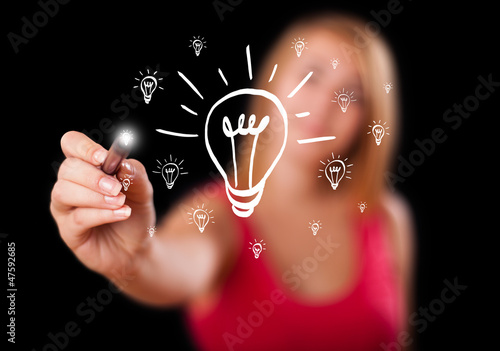 Photo: Woman drawing light bulb on whiteboard Woman drawing light bulb on whiteboard