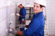 Electricians wiring a large white tiled room
