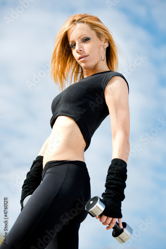 Photo: Beautiful fit woman exercising outdoors over a sky background Beautiful fit woman exercising outdoors over a sky background