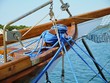 A blue rope on a belaying cleat of a wooden ship