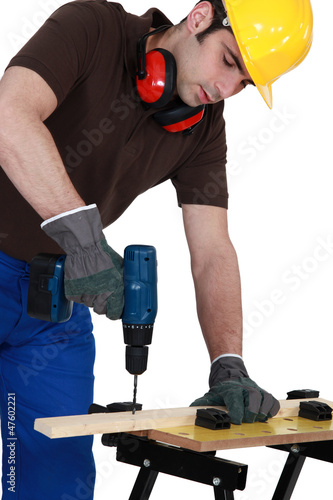 Photo: Workman drilling a hole into a wooden plank Workman drilling a hole into a wooden plank