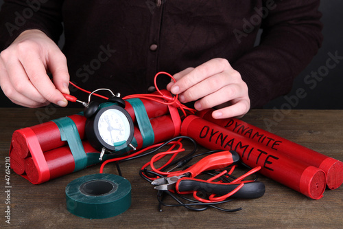 Photo: Human makes timebomb on wooden table on black background Human makes timebomb on wooden table on black background