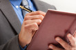 Businessman writing on his agenda