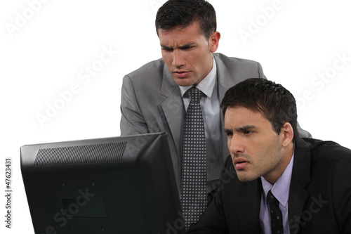 Photo: Two serious businessman concentrating on laptop screen Two serious businessman concentrating on laptop screen
