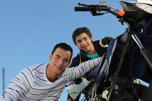Photo: man and teenager watching motorbike man and teenager watching motorbike